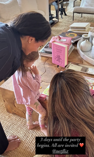 Meghan Markle and Princess Lilibet playing Candy Land on a wood coffee table with Serena Williams in Meghan's living room