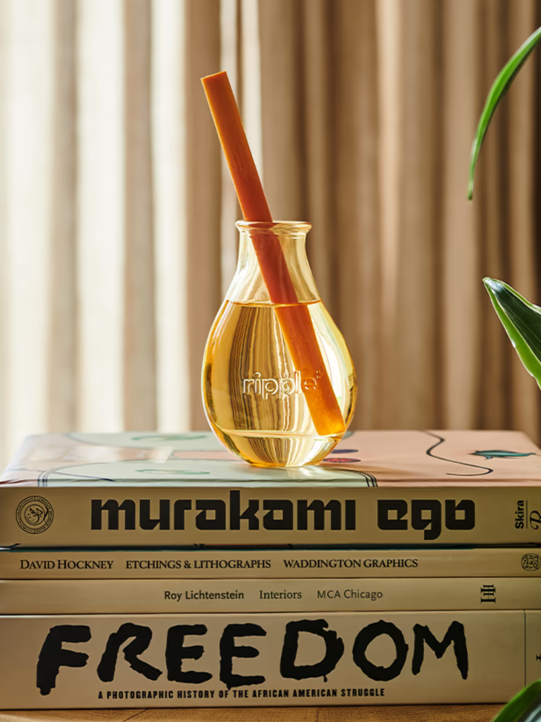 An orange reed diffuser on a stack of books