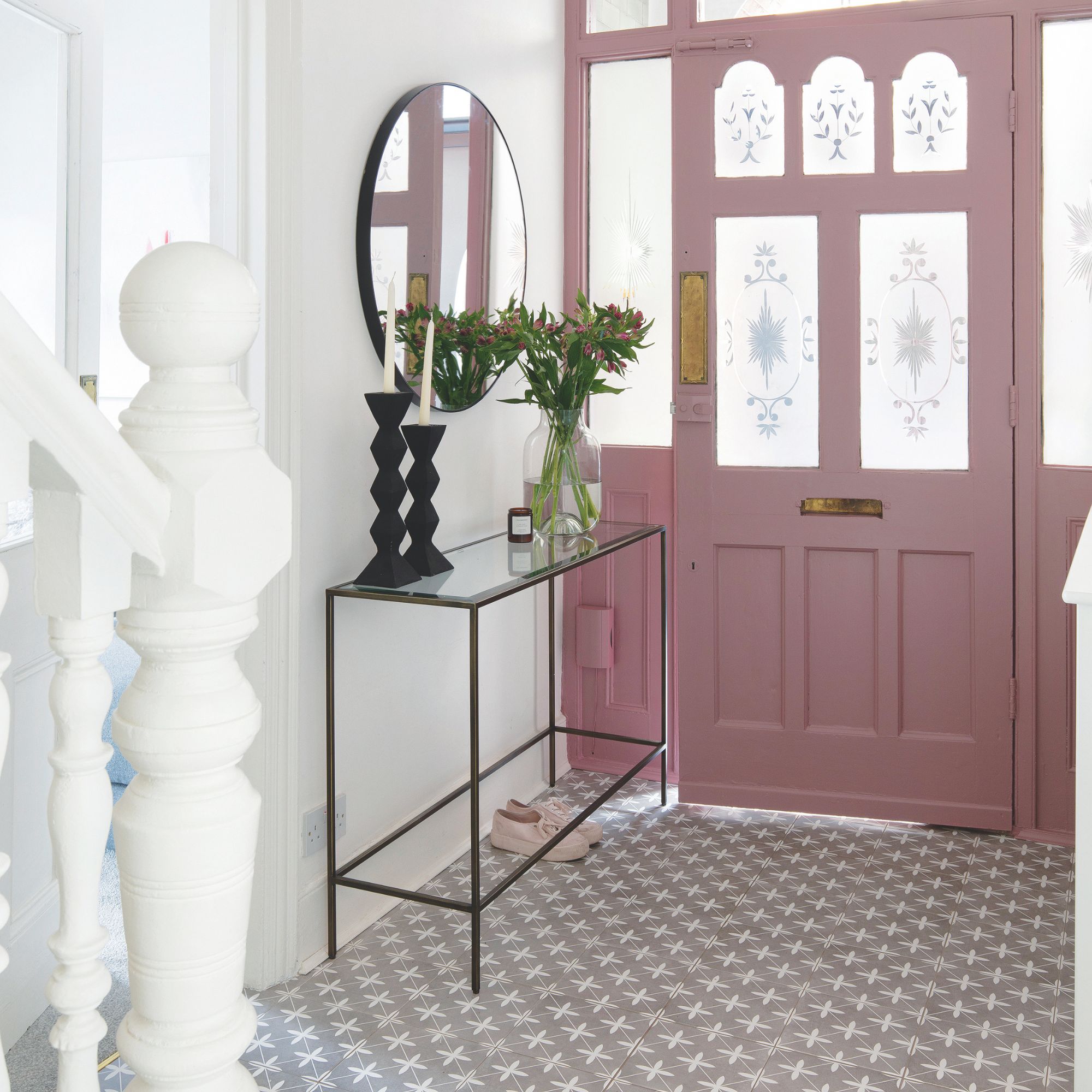 Hallway with white painted walls, patterned tiled floor and a pink front door