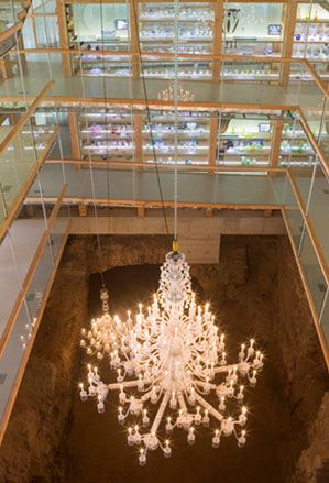 Interior view from the viewing gallery at the La Grand Place, Musée du Cristal Saint-Louis, chandelier lit up, glass fronted display windows, walkways, glass barriers with wooden frame