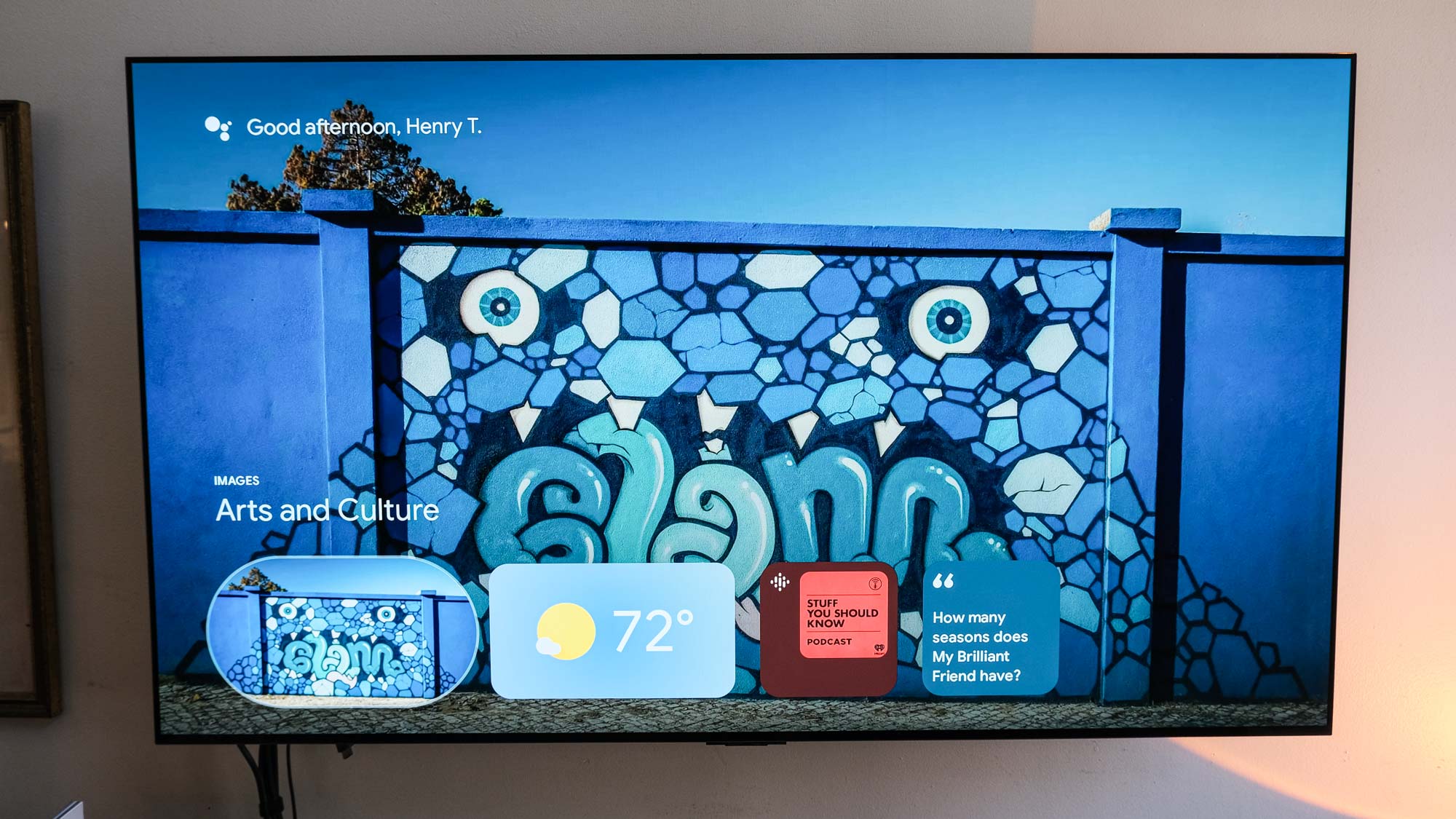 The Google TV streaming box 4K screensaver on the TV screen features elaborate rock monsters graffiti on the wall