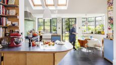 Steel-framed windows and doors open the kitchen up to the garden. Kitchen features cool slate floor tiles and a table and chair set