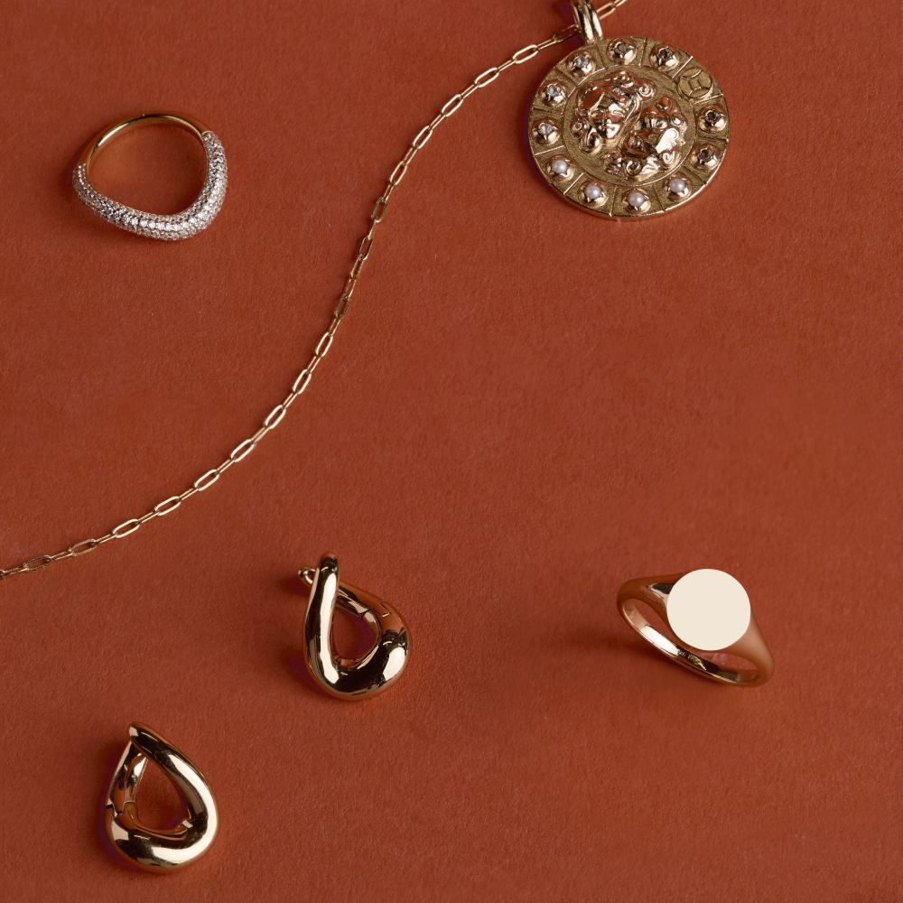 Gold Astrid & Miyu jewellery on a burnt orange background