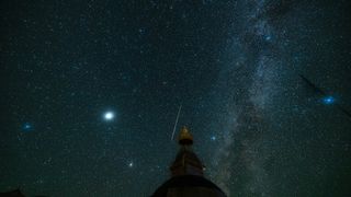 a streak of light zooms among the stars in the night sky