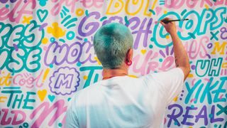 Aries Moross, one of the most famous graphic designers, writing colourful text on a canvas