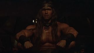 Arnold Schwarzenegger sits in a hut in the movie Conan the Barbarian