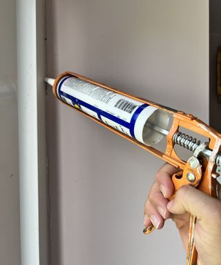 A person holding waterproof sealant and applying around a sliding door