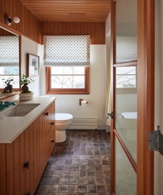 narrow bathroom with wood paneling, shiplap ceiling, tiled floor, blind, white countertop