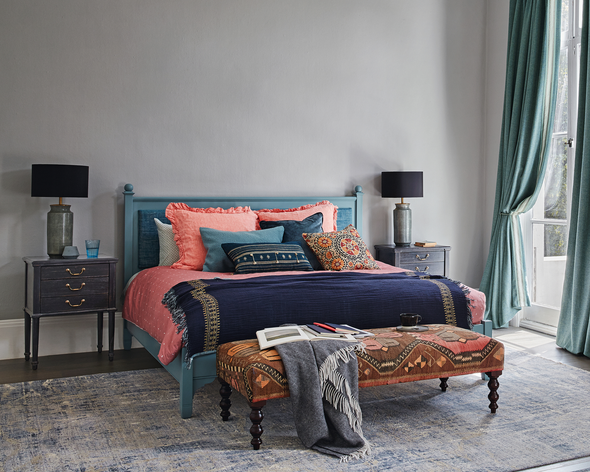 A grey bedroom idea with coral and blue colored bed linen