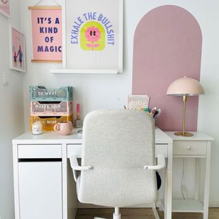 Bright WFH setup with colorful desk organizers, a white desk and chair in front of a pink color block wall