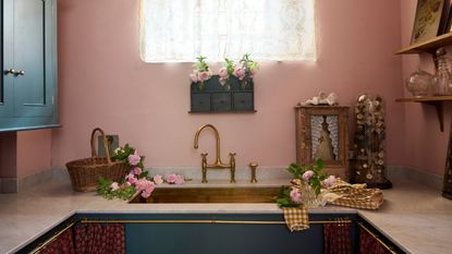 laundry room with pink walls, dark blue cabinets and brass taps