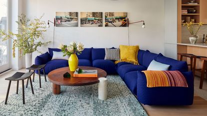 a living room with a blue sofa with yellow accessories