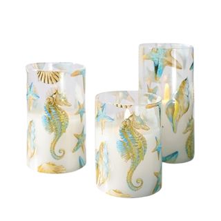 Three flameless candles with coastal designs on them