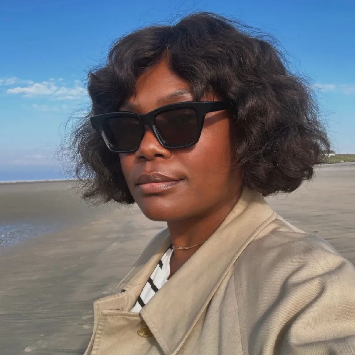 Creator @frannfyne taking a selfie on the beach with a tousled, wavy bob