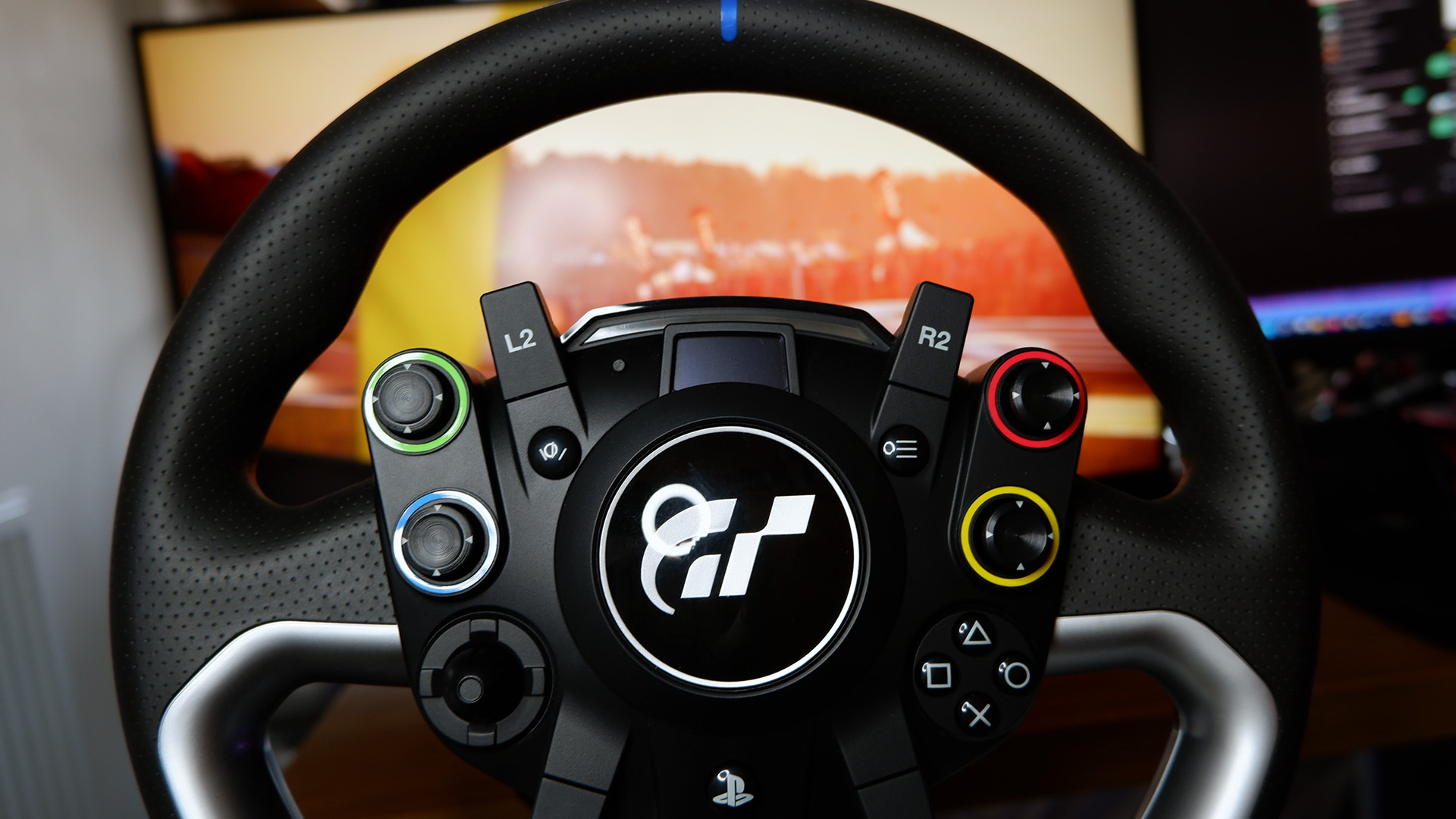 The Fanatec GT DD Pro racing wheel and wheelbase on a desk with monitor playing Assetto Corsa behind.