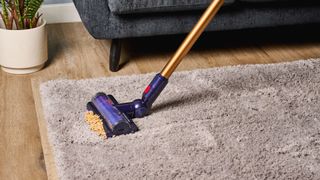 the dyson gen5detect cordless stick vacuum in prussian blue and copper, showing its cleaning head and attachment tools