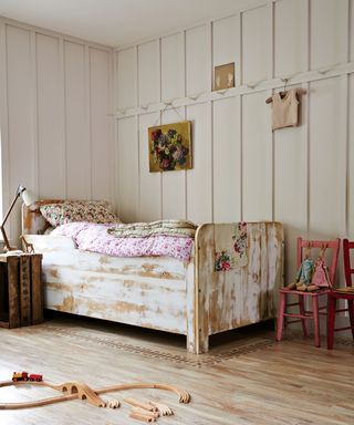 Girl's bedroom with white paneling and distressed bed by Amtico