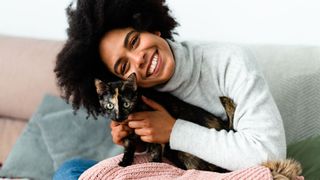 Woman smiling while hugging cat