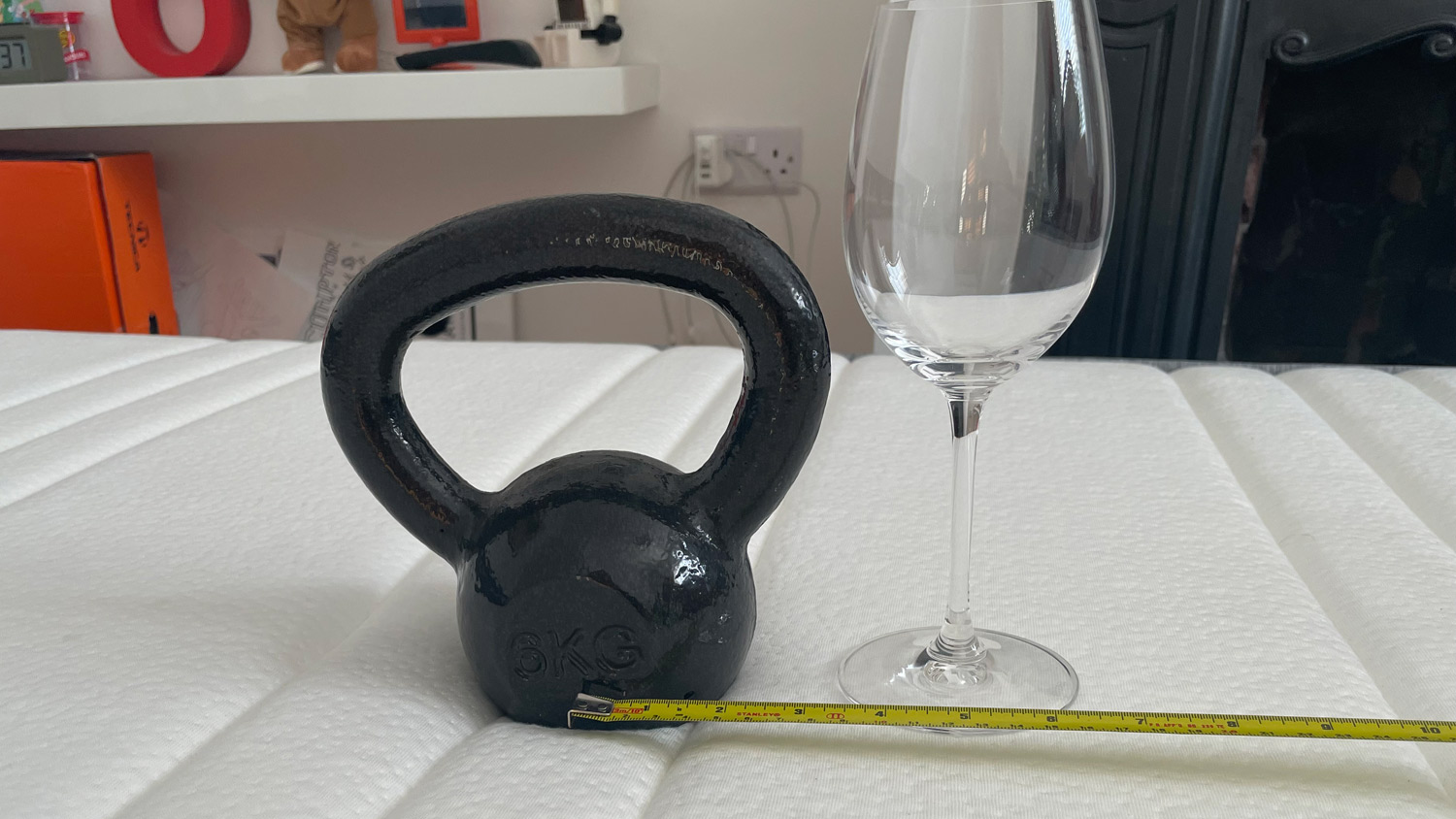 A weight, a wine glass and a tape measure on the Origin Hybrid Mattress