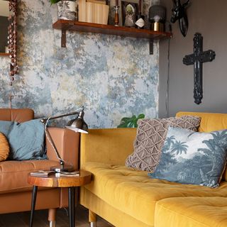 Living room with yellow and leather sofas, wallpaper, task lamp, crucifix, open shelf