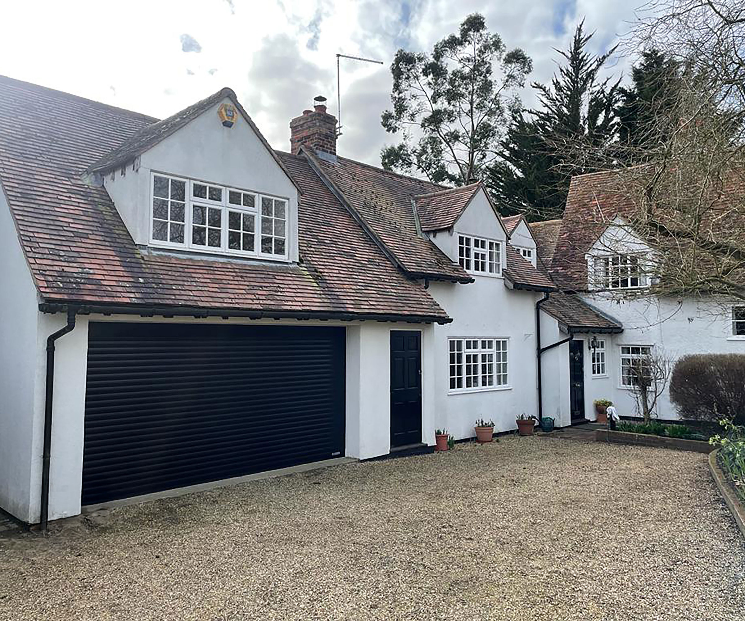gravel driveway with white house with black roller garage doors