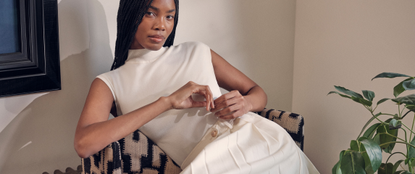 Model wearing a cream Karen Millen dress slouching on a chair