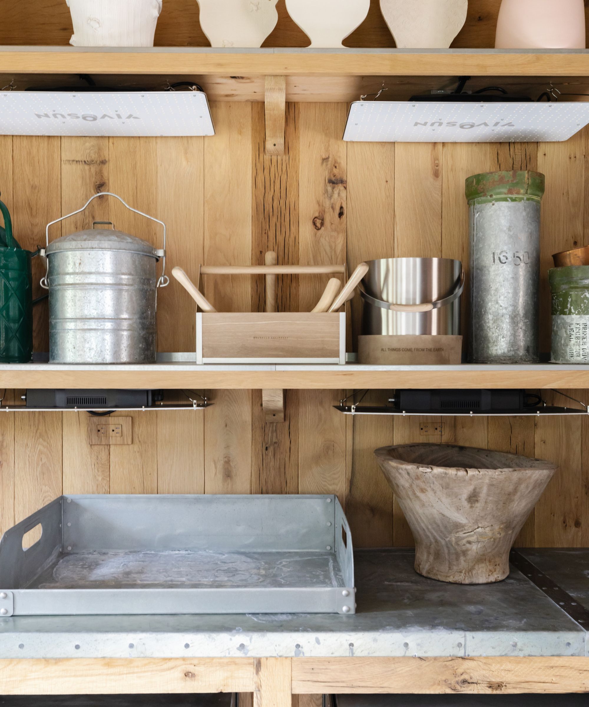 Wooden shelving in a shed with various boxes and tins on them.