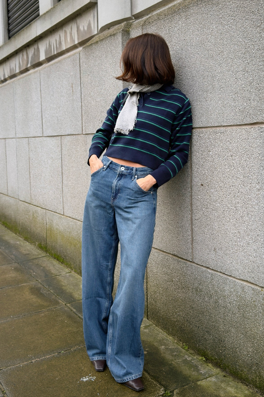 a woman wearing polo shirts, baggy jeans, pointed toe shoes