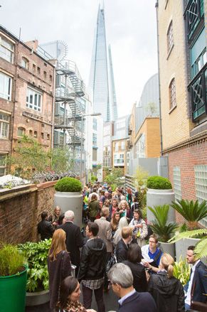 View of Gibbon's Rent alley filled with people and green plants in grey and green pots during the day