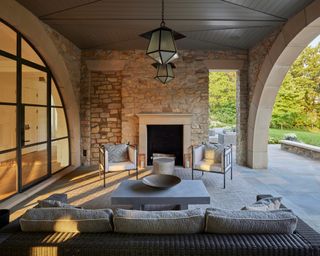 loggia with sofa, chairs, fireplace and statement pendants