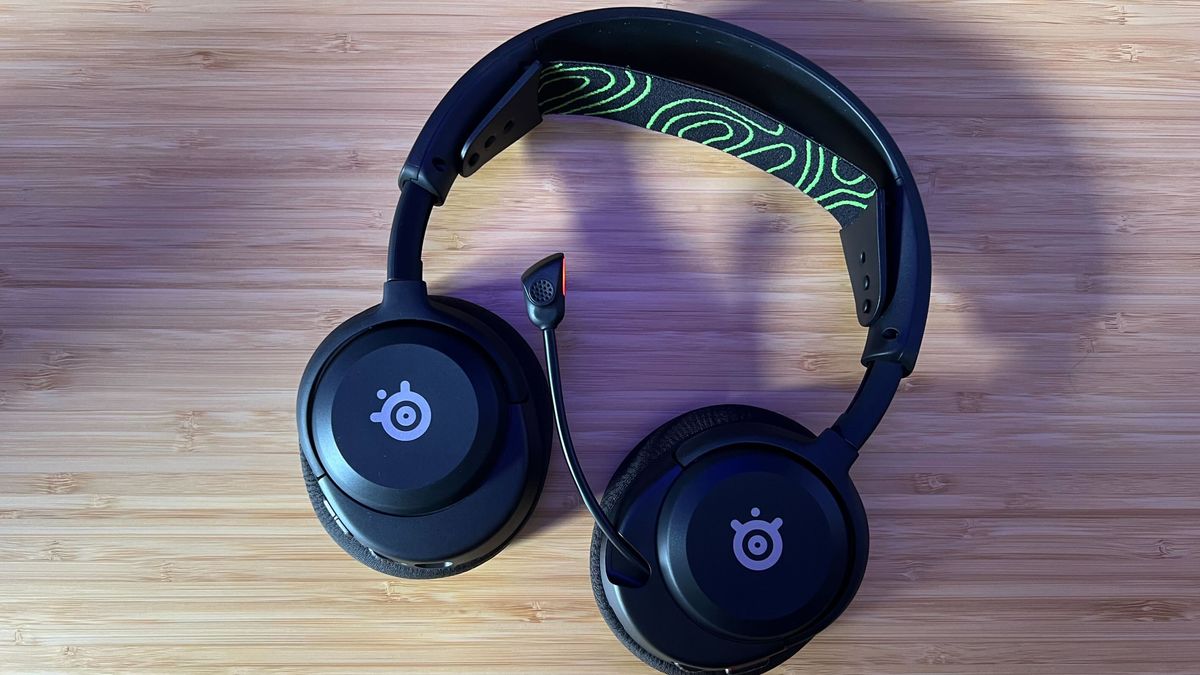 SteelSeries Arctis Nova 5 Wireless gaming headset laid flat on a wooden table with microphone extended