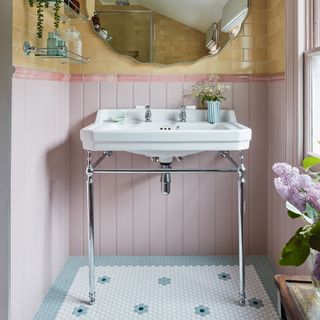 ensuite bathroom with yellow tiles on the top half of the walls and pink panelling on the lower part, small blue and white mosaic tiles on the floor