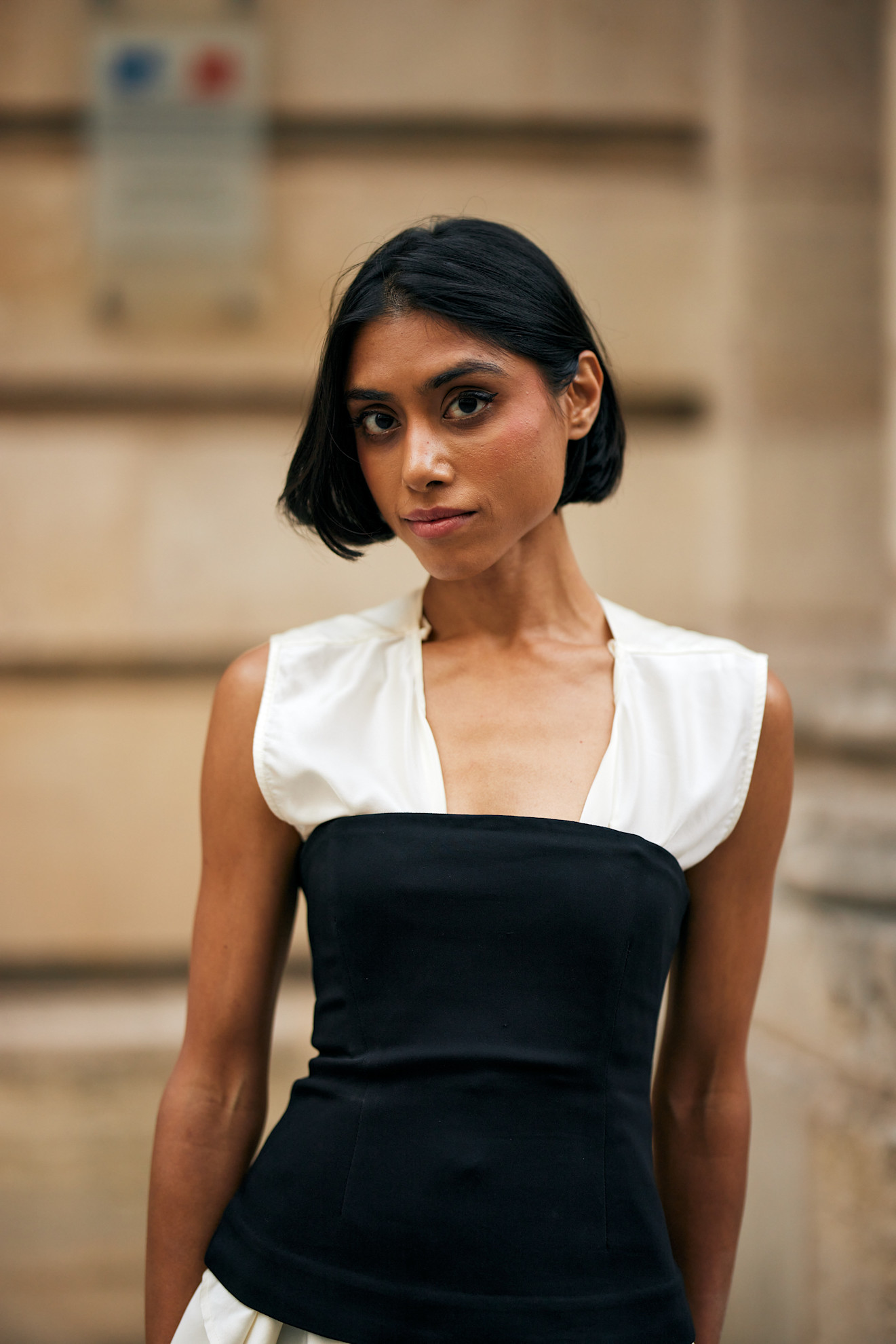 a woman with a dark brown bob wearing a black and white dress