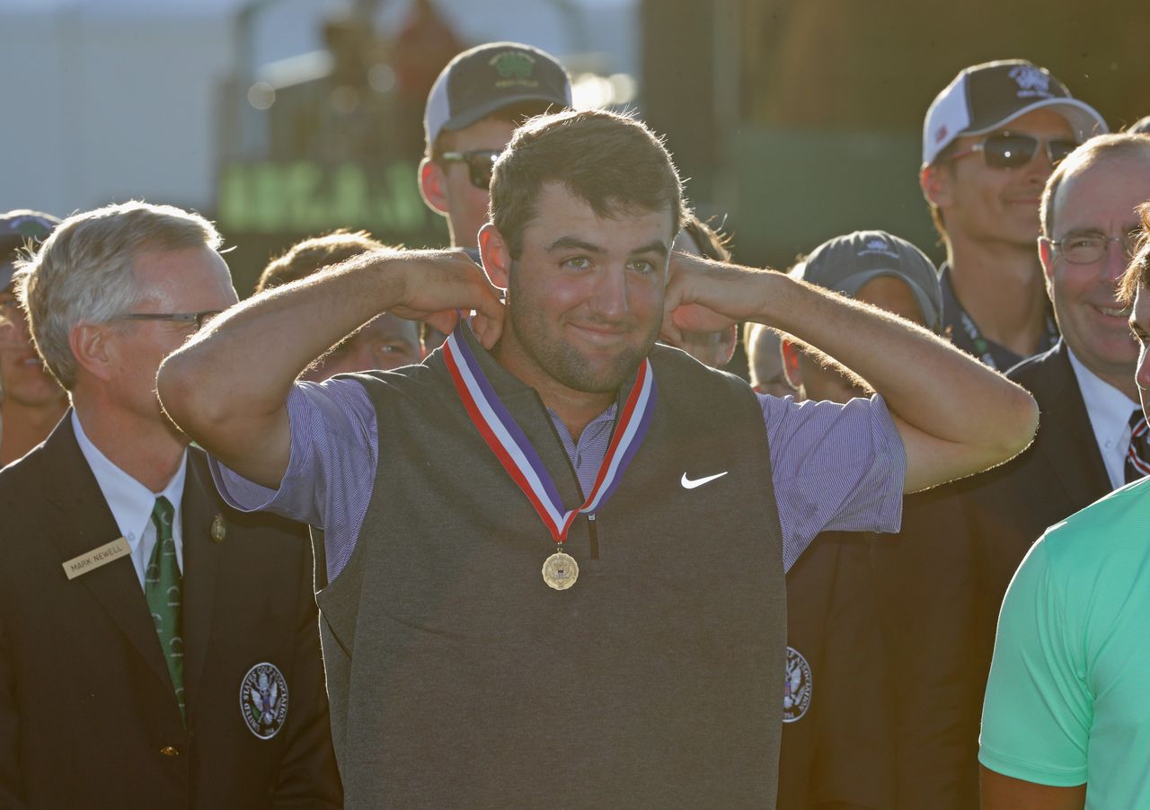 Scottie Scheffler puts a medal on