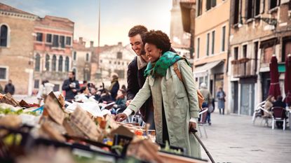 A tourist couple in Venice pause to look at the offerings at a street market.