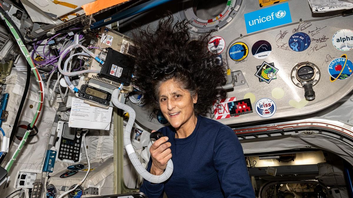 a woman talks into a radio handset while her hair floats in zero gravity around her