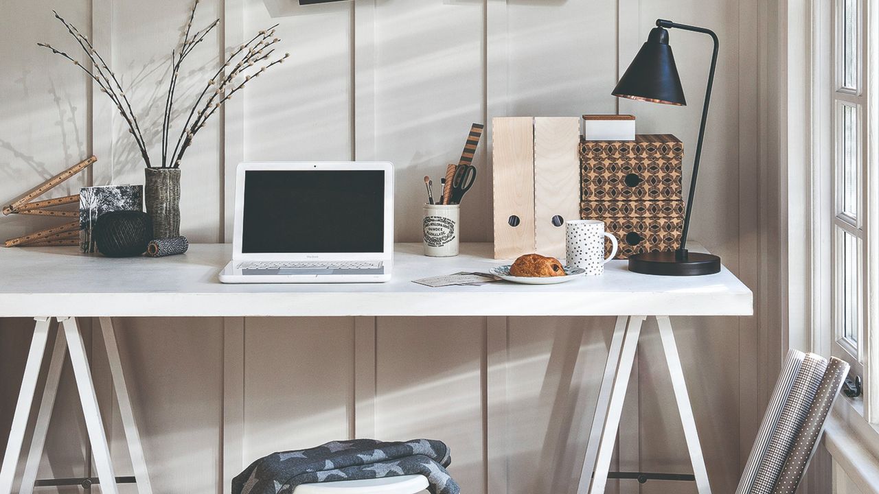 A wall-panelled home office in white with a matching desk and minimal decor