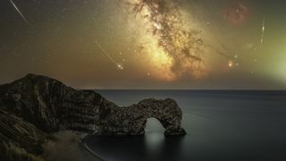 A stunning night sky over a rocky coastline, featuring the Milky Way, shooting stars, and a unique rock arch formation