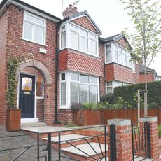 Brick house with driveway and a black gate in front of it