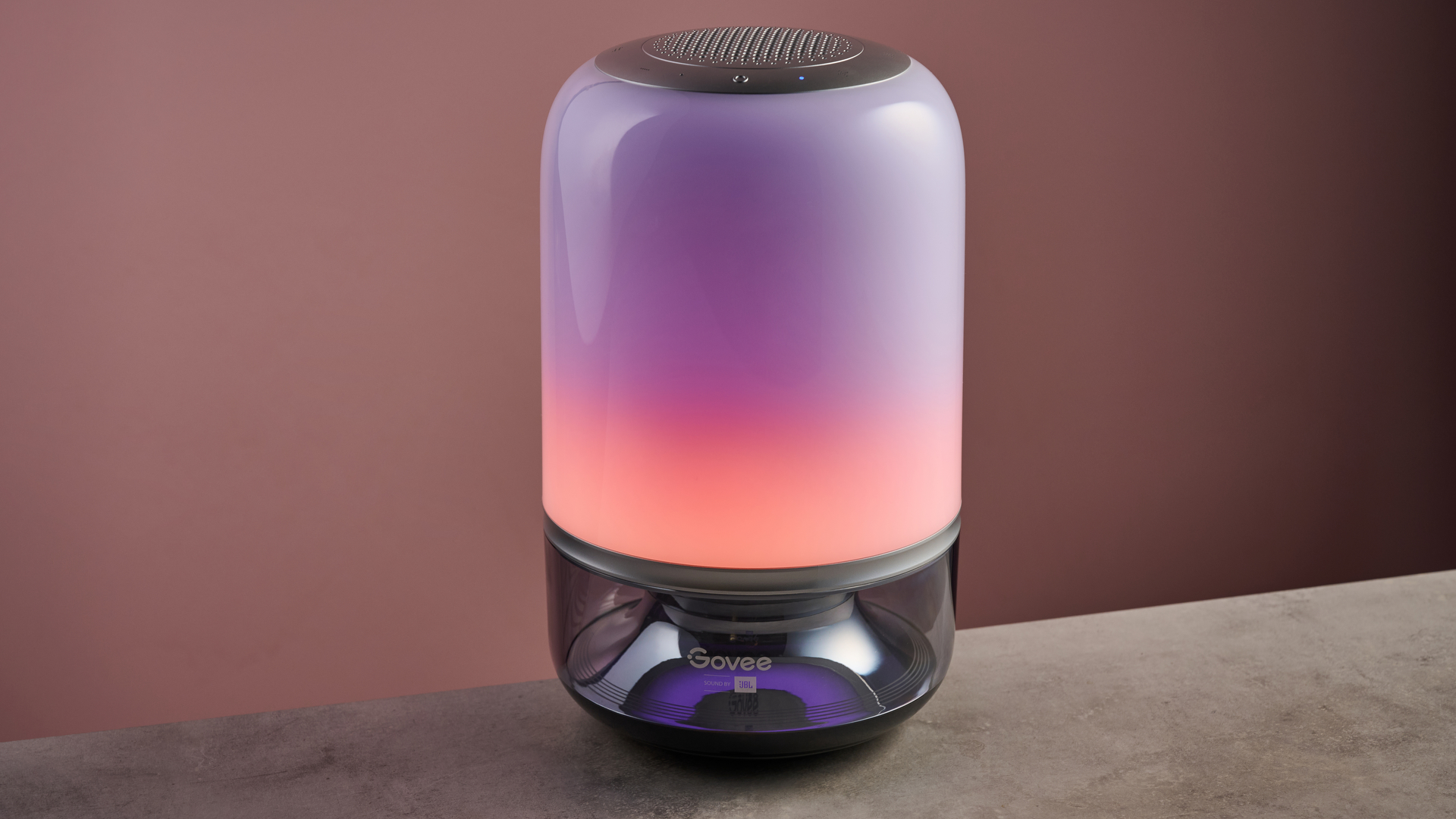 The Govee Table Lamp 2 Pro x Sound by JBL is shown in a dark room and is showing a pink and purple sunset effect.