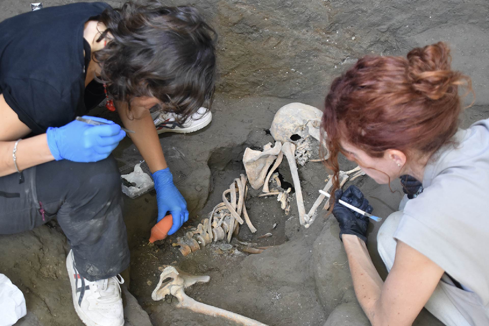 two female archaeologists examining a skeleton 