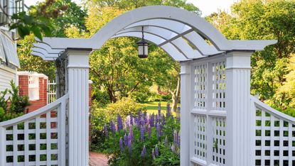 garden arbor ideas: grey arch over path with hanging light