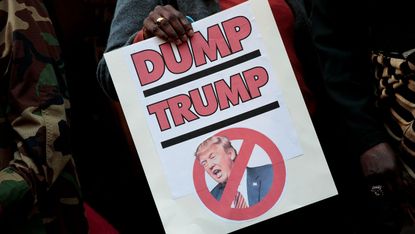 A woman holds an anti-Trump sign at a protest in 2016
