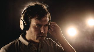 Man wearing a set of headphones on a dark background