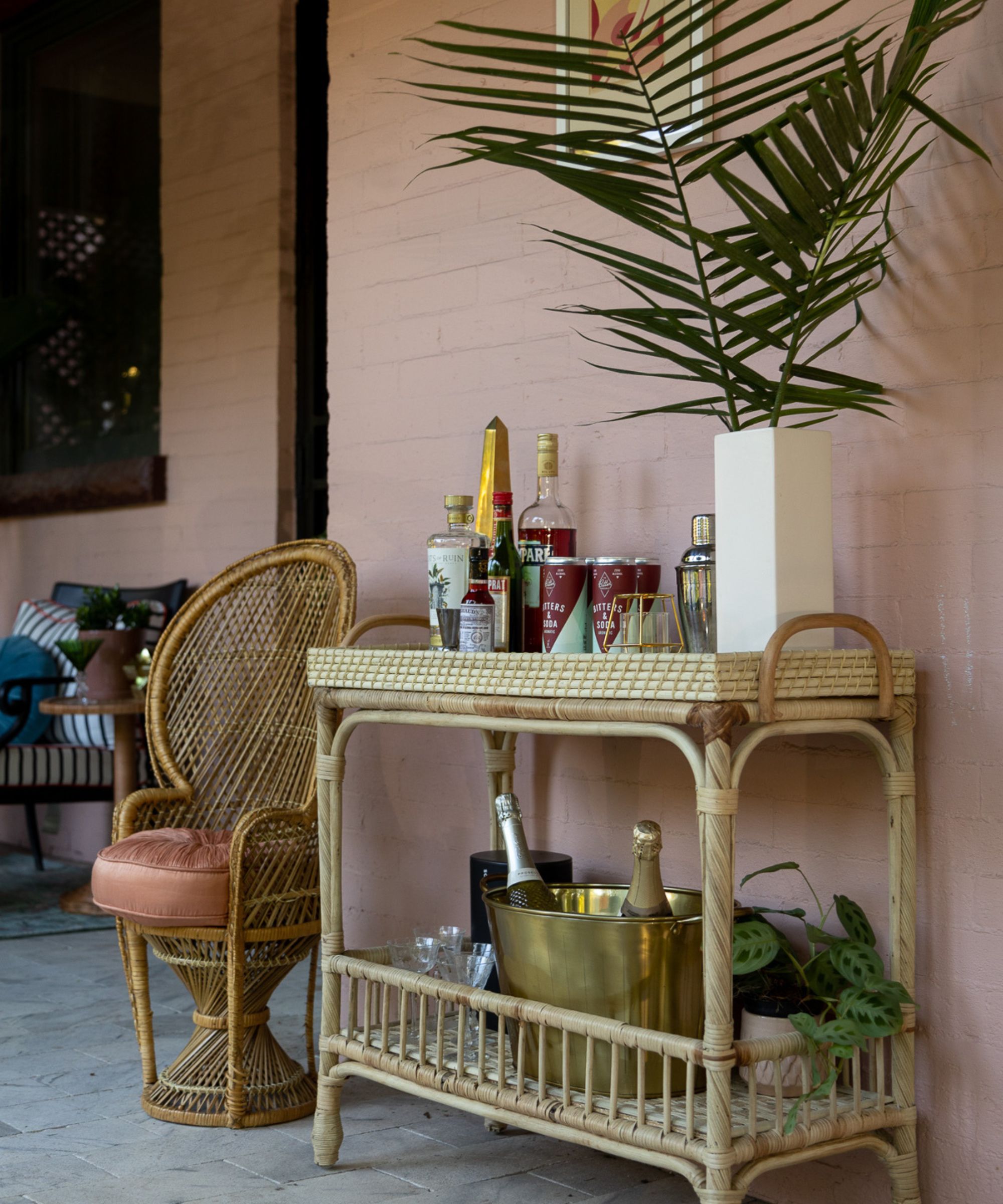 Rattan bamboo bar cart styled with cocktail making drinks and a champagne bucket outdoors