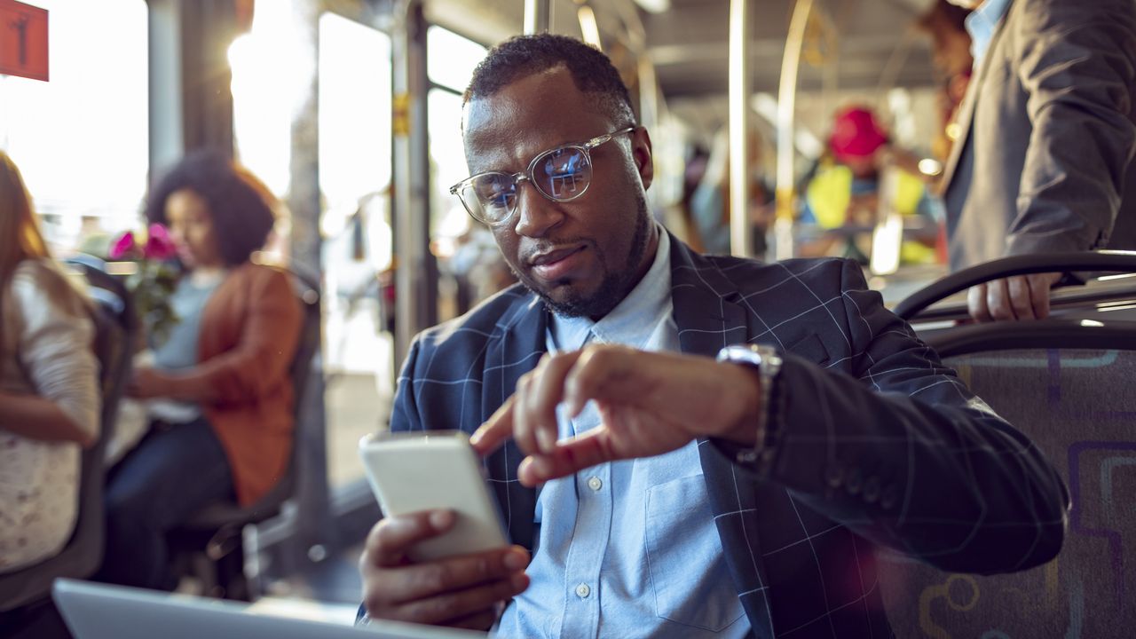 A man on a subway train uses his smartphone.