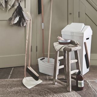 cleaning accessories with brushes and dustbin in white cupboard