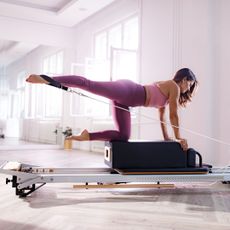 A woman doing one of the best intermediate Pilates exercises on a Reformer machine