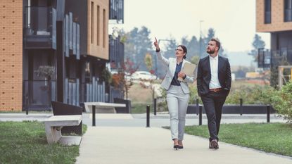 A man and a woman walk through an apartment community, evaluating it as they go..