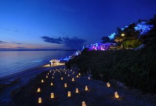 White Night at the beach at Sani Resort. Candles light the way, and disco lights illuminate the bar and beach where guests are dancing